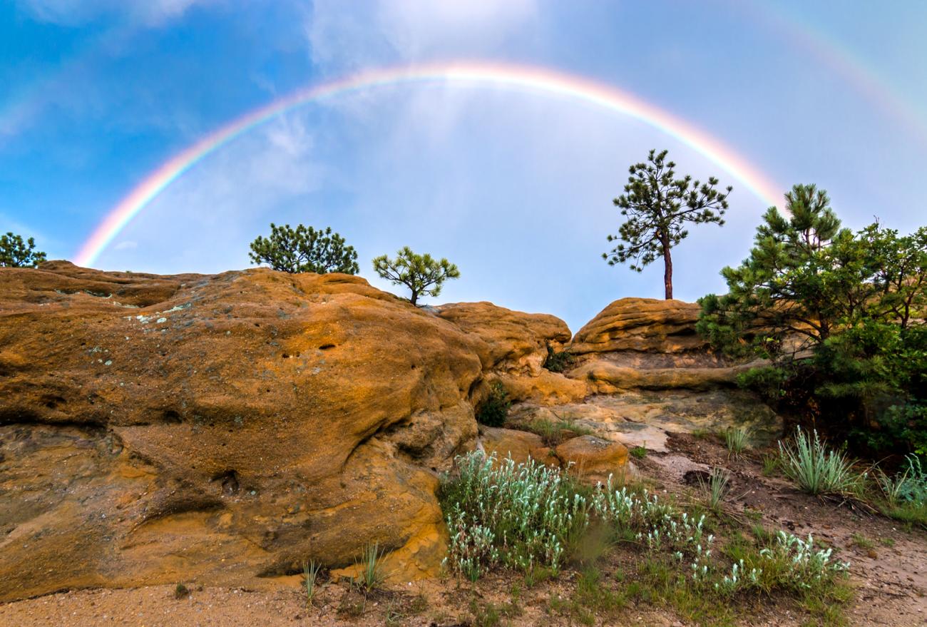 photo of a double rainbow above rocky bluffs